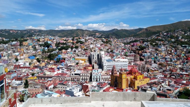 Vista panorámica de la ciudad de Guanajuato, con las casas de colores en las laderas y la basílica amarilla en el centro.